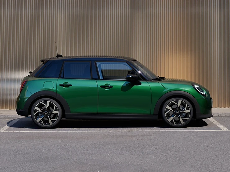 MINI Cooper 5 Kapı, British Racing Green gövdesi ve siyah tavanıyla park halinde yan profilden görünüşü.