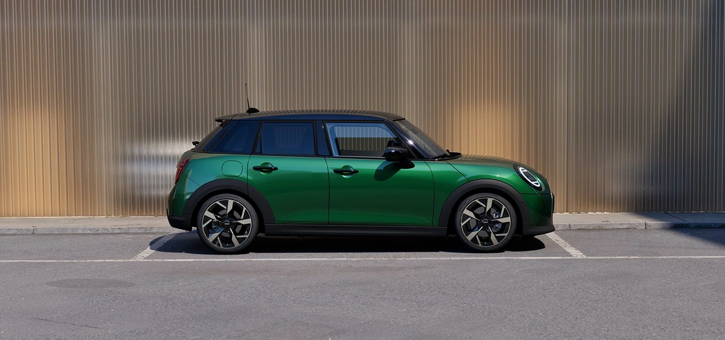 MINI Cooper 5 Kapı, British Racing Green gövdesi ve siyah tavanıyla park halinde yan profilden görünüşü.