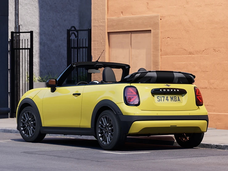 Sunnyside Yellow rengi MINI Cooper Cabrio’nun park halindeyken arkadan sol açıdan görünümü.