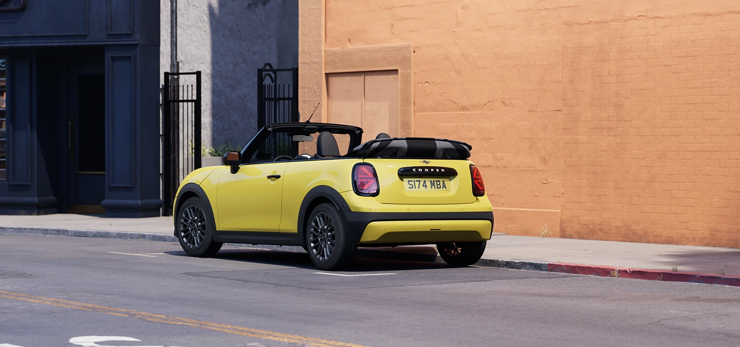 Sunnyside Yellow rengi MINI Cooper Cabrio’nun park halindeyken arkadan sol açıdan görünümü.