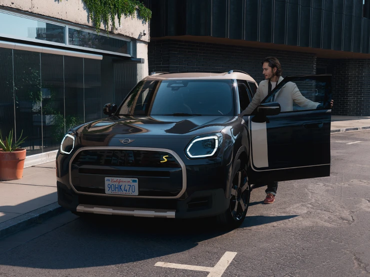 Tamamen Elektrikli MINI Countryman'ın Midnight Black ve Vibrant Silver Roof ile sokakta ön görünümü.