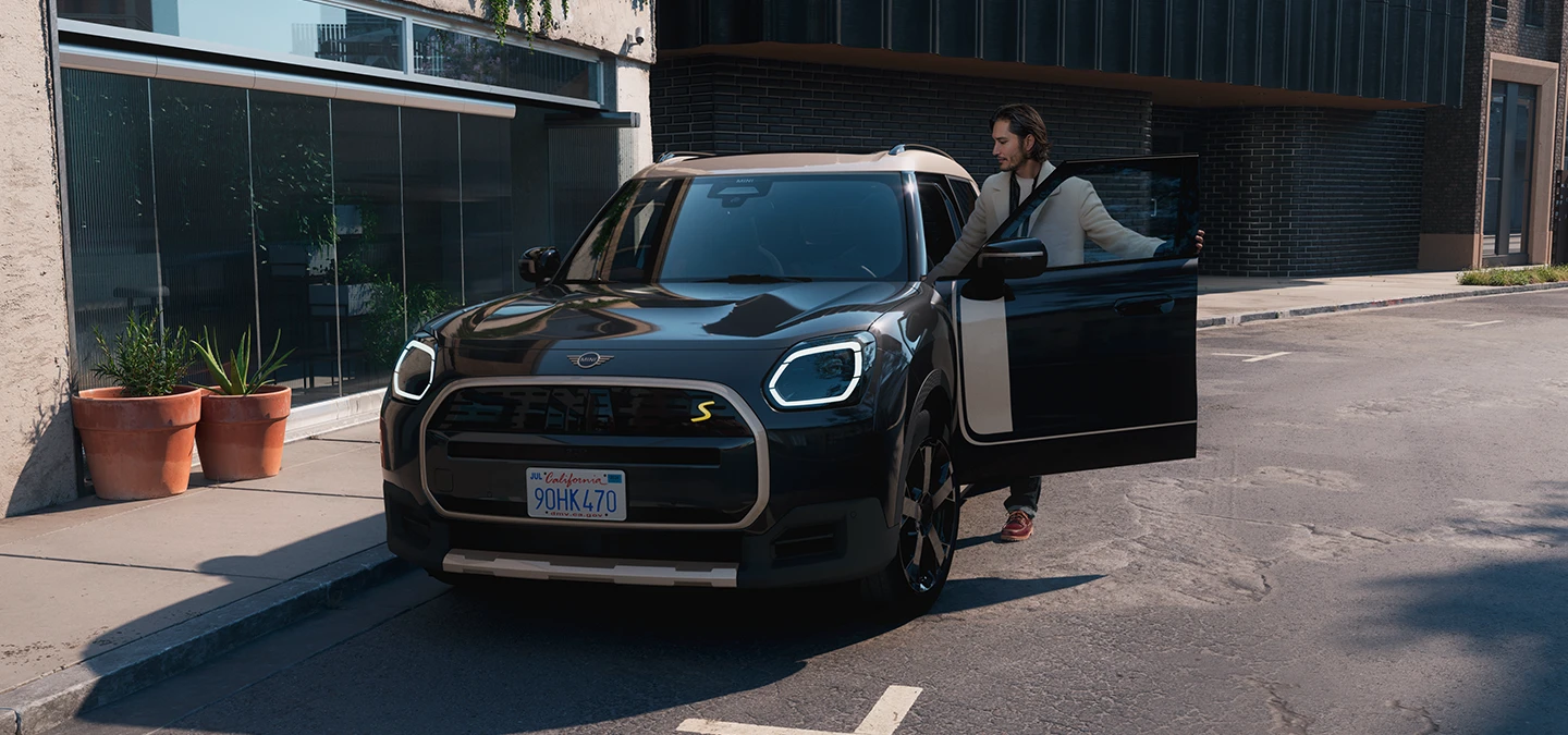 Tamamen Elektrikli MINI Countryman'ın Midnight Black ve Vibrant Silver Roof ile sokakta ön görünümü.