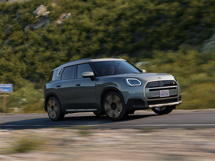 Vibrant Silver Roof offroad özelliğine sahip Smokey Green modelinde tamamen elektrikli MINI Countryman'ın yandan görünümü.