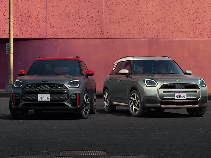 MINI Countryman JCW'nin Legend Grey ve Red Roof ile yan yana duran Smokey Green ve Vibrant Silver Roof modellerinin önden görünümü.