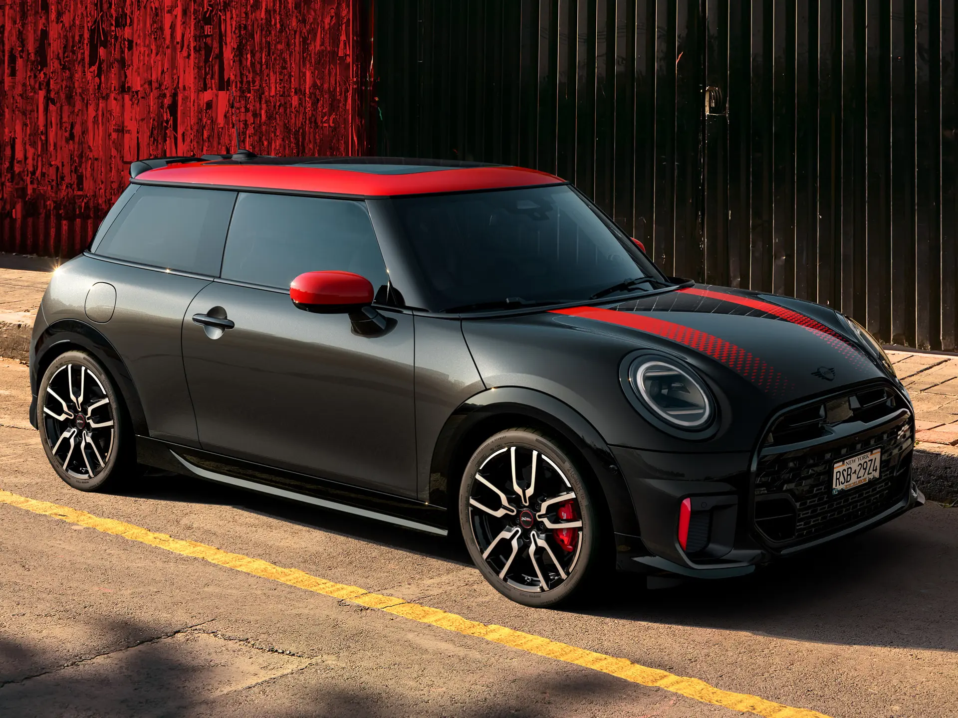 Chili Red renginde tavan ve ayna kapaklarına sahip, Midnight Black gövde renginde MINI John Cooper Works 3 kapı, yandan görünüm, caddede park halinde.