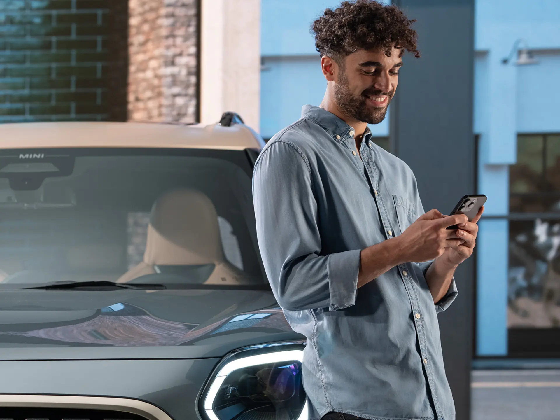 MINI kişiselleştirilmiş servis randevuları - MINI'nin yanında telefonuna yazan bir adam