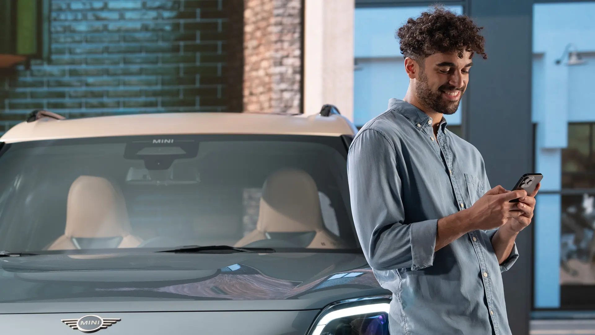 MINI kişiselleştirilmiş servis randevuları - MINI'nin yanında telefonuna yazan bir adam