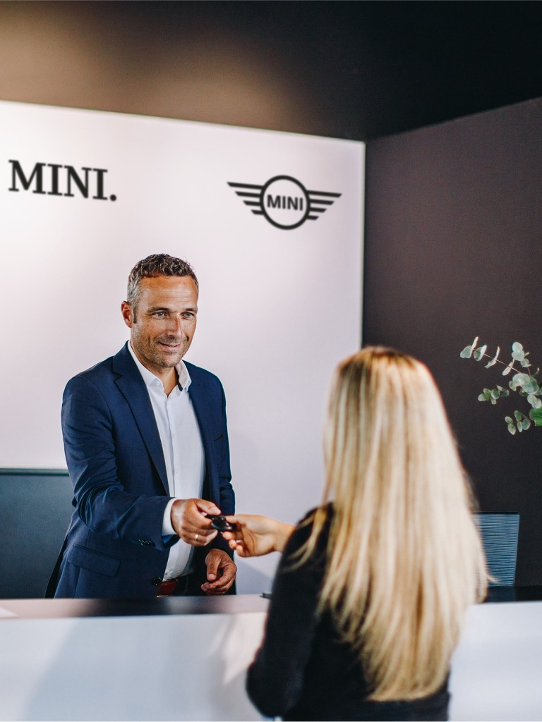 MINI Yetkili Servis Merkezinde otomobilin anahtarını sarışın bir kadına teslim eden MINI Yetkili Servis temsilcisi